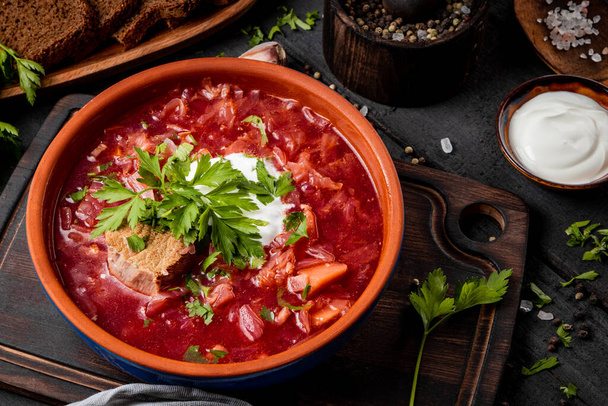 Borscht with sour cream in earthenware on the table close-up - a dish of traditional Russian and Ukrainian cuisine. High quality photo - Fotó, kép