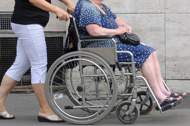 hendikepovaná žena na vozíku a dívka pomáhá na ulici  - Fotografie, Obrázek