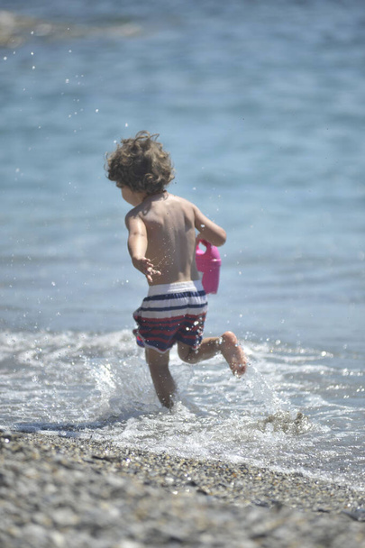 Boy children plays near the sea in the beach during the summer - Fotoğraf, Görsel