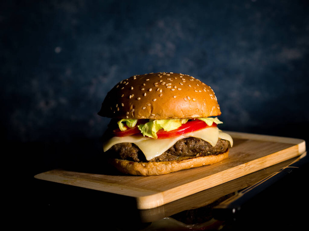 A closeup of hamburger served on a wooden surface - Foto, afbeelding