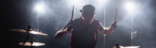 Rock zenekar tagja dobverők játszik dob háttérvilágítással és füst a háttérben, banner - Fotó, kép