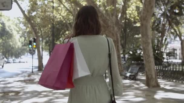Zadní pohled na ženu držící tašky na rameni a chůzi - Záběry, video