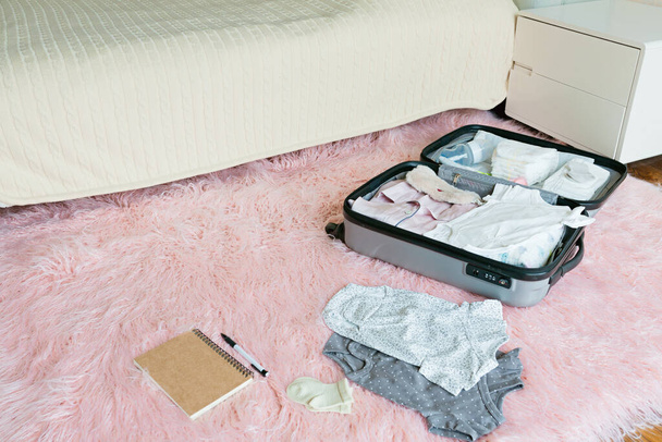 Young Pregnant woman packing suitcase for maternity hospital at home, closeup. Checklist for childbirth. Pregnancy during coronavirus covid-19 pandemic. High quality photo - Valokuva, kuva