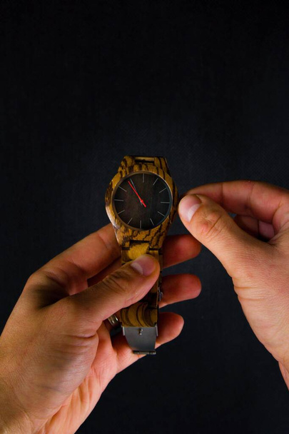 Un hombre estira un reloj de pulsera y ajusta el tiempo. - Foto, Imagen