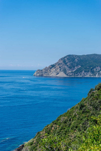 Europe, Italy, Cinque Terre, Corniglia, a body of water with a mountain in the background - Foto, afbeelding