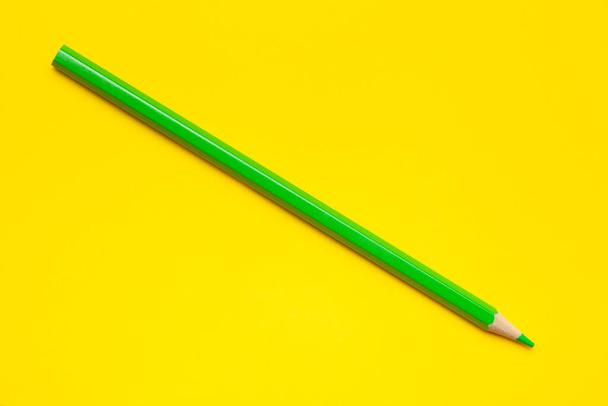 diagonal green sharp wooden pencil on a bright yellow background, isolated, copy space, mock up - Foto, afbeelding