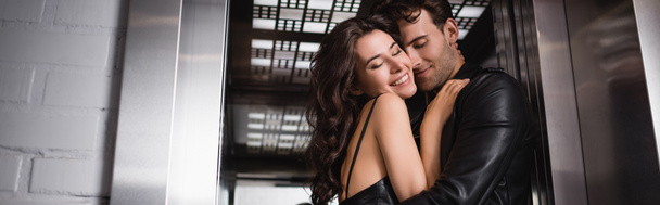 Heureux jeune couple adulte avec les yeux fermés s'embrassant à l'entrée de l'ascenseur, bannière - Photo, image