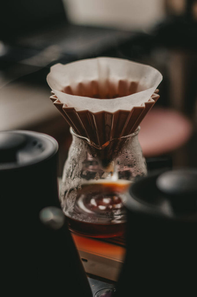 A soft focus of a pour over coffee set-up using cone dripper and glass decanter - Fotó, kép