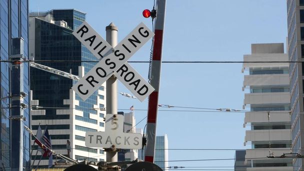 Tasoristeys varoitussignaali Yhdysvalloissa. Crossbuck ilmoitus ja punainen liikennevalo rautatie risteyksessä Kaliforniassa. Rautatieliikenteen turvallisuustunnus. Varoitusmerkki vaarasta ja junaradasta. - Valokuva, kuva