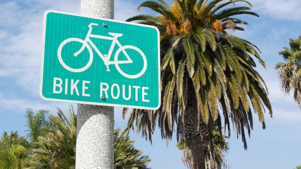Велосипедний дорожній знак в Каліфорнії, США. Велосипедна смуга. Велосипед в Океансайді - пацифічний туристичний курорт. Cycleway signboard and palm Здоровий спосіб життя, відпочинок і безпечний велосипед символ. - Фото, зображення