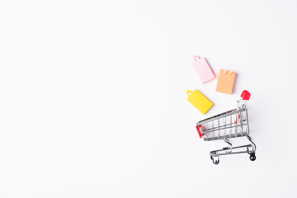 Top view of toy shopping bags near cart on white background - Photo, image