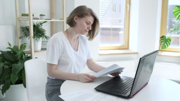 Laptop bilgisayarında çalışan beyaz bir kadın. Ekrana bakıyor, gülüyor. - Video, Çekim