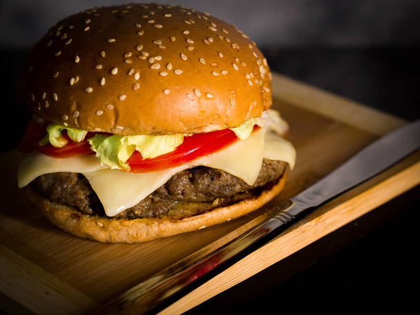 A closeup of hamburger served on a wooden surface - Fotoğraf, Görsel