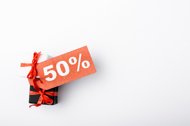 Top view of price tag with 50 and percent signs on toy gift boxes on white background - Φωτογραφία, εικόνα