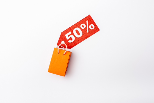 Vista superior de la etiqueta de precio con 50 por ciento de signos y bolsa de compras de juguete sobre fondo blanco - Foto, imagen