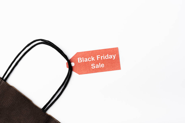 Top view of shopping bag and price tag with black friday sale lettering on white background - Foto, imagen
