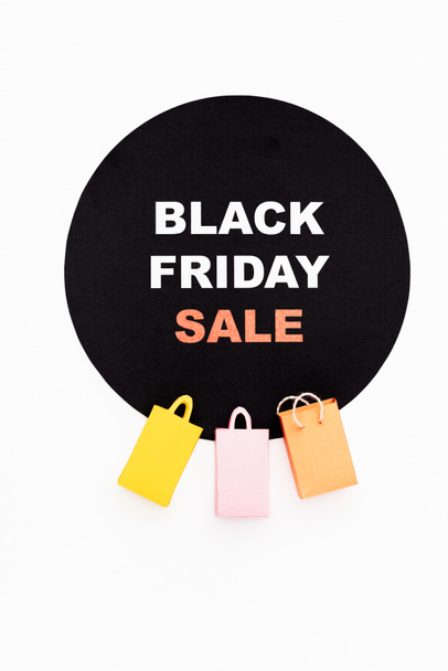 Top view of colorful toy shopping bags near black circle with black friday lettering on white background - Foto, Imagen