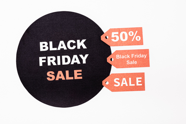 Top view of red price tags near black circle with black friday lettering on white background - Photo, Image