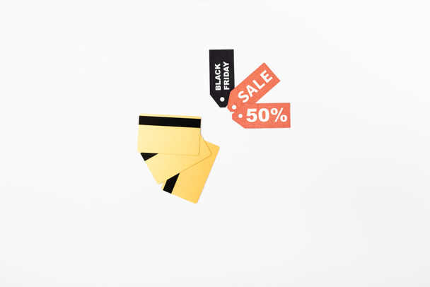 Vista superior de tarjetas de crédito y etiquetas de precios con letras de viernes negro y venta sobre fondo blanco - Foto, imagen