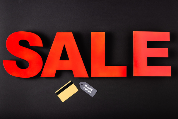 Vista superior de la tarjeta de crédito cerca de etiqueta de precio y negro viernes venta de letras sobre fondo negro  - Foto, imagen