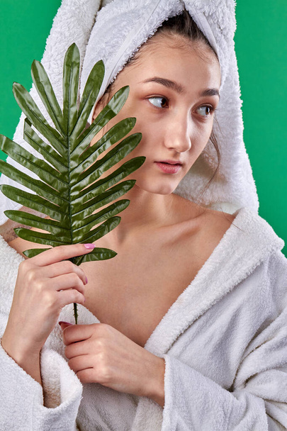 Young girl in bathrobe posing with herb. - Фото, зображення