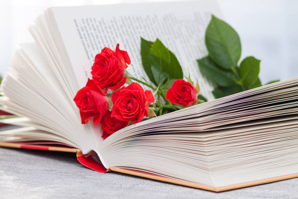 Un libro abierto con rosas naranjas rojas. Lectura y relax. Romántico, dulce, citas concepto. - Foto, Imagen
