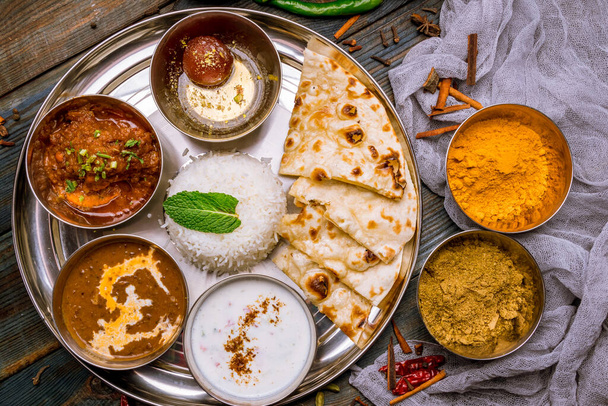Sortiment indické jídlo set na dřevěném pozadí. Jídla a předkrmy z kuchyně, rýže, čočky, paneer, samosa, koření, masala. Mísy a talíře s indickým jídlem - Fotografie, Obrázek