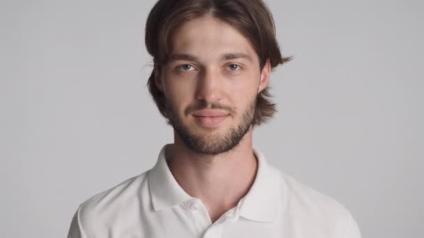 Ritratto di bel ragazzo barbuto guardando con fiducia in macchina fotografica su sfondo bianco - Filmati, video