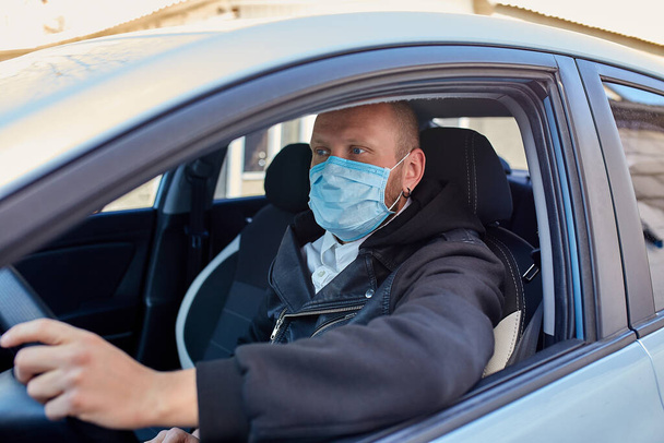 Muž s ochrannou maskou přijíždějící autem v koronavirové pandemické karanténě. Prevence infekcí a kontrola epidemie. Světová pandemie. Zůstaň v bezpečí.. - Fotografie, Obrázek