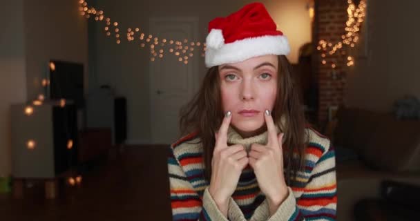 Depressed lady in Christmas hat makes smile with fingers - Filmagem, Vídeo