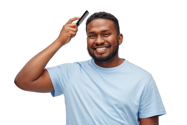 happy african american man brushing hair with comb - Photo, image