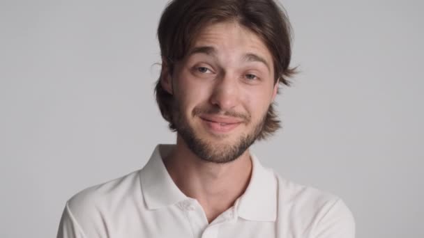 Portret atrakcyjnego wesołego faceta szczęśliwie patrzącego w kamerę na białym tle - Materiał filmowy, wideo