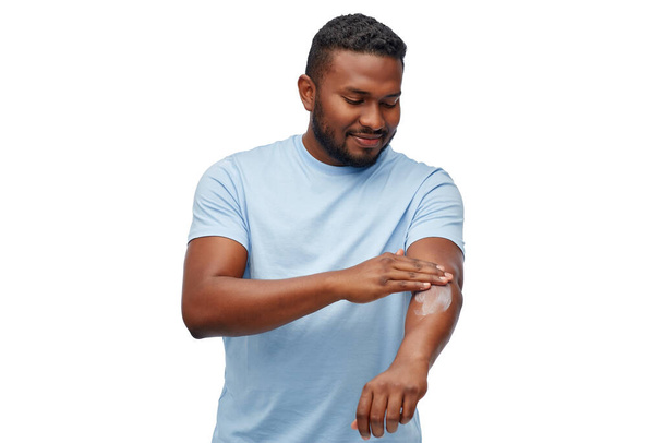 heureux homme africain appliquant hydratant à sa main - Photo, image