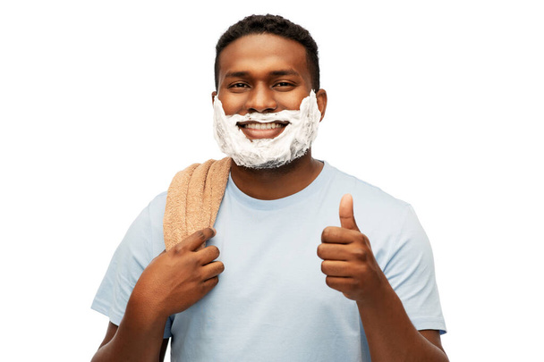 smiling african man with shaving foam and towel - Photo, image