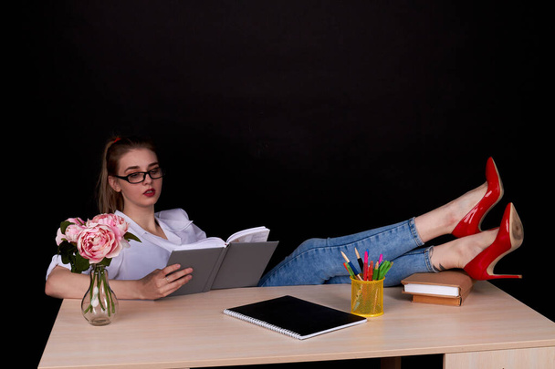 Serious female teacher with her red shoes on the table. - Foto, immagini