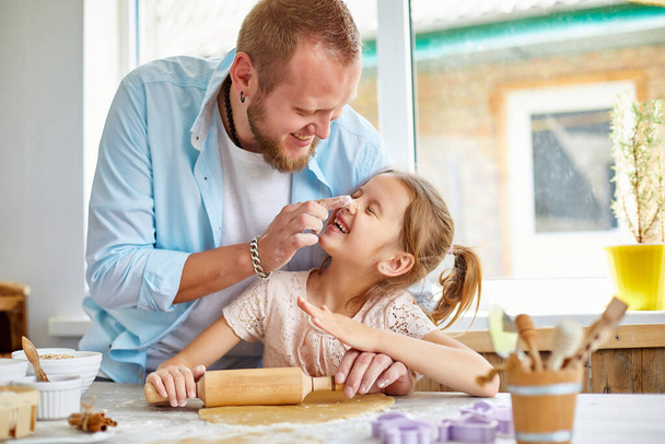 Famille heureuse, père et fille déploient la pâte à biscuits dans une cuisine à la maison, concept de paternité et week-end familial, père et enfant jouent ensemble. - Photo, image