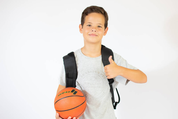 Boldog fiatal iskolás fiú kezében egy labdát. Fehér alapon elszigetelve - Fotó, kép