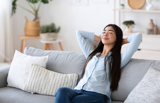 Home Comfort. Jeune dame asiatique se détendre sur canapé confortable dans le salon - Photo, image