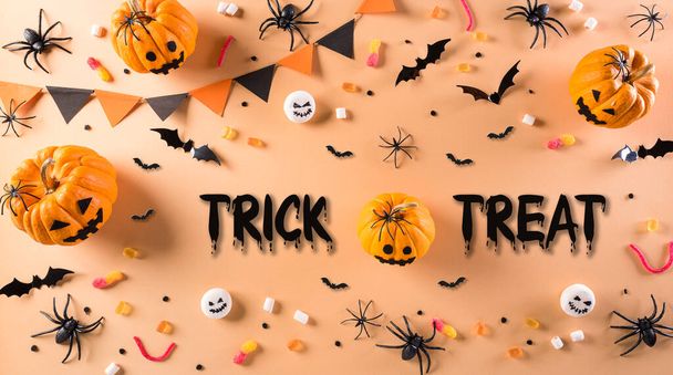 Top view of Halloween crafts, orange pumpkin, ghost, bat and black spider on pastel orange background. Flat lay, top view with Trick or Treat text. - Photo, Image