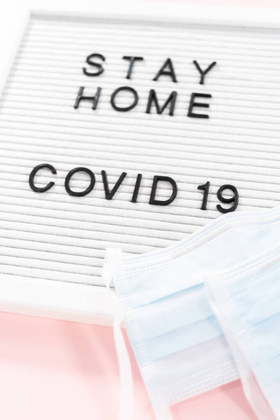 STAY HOME und COVID-19 Schild auf der Tafel mit blauer medizinischer Maske. - Foto, Bild