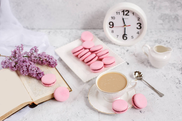 Una taza de café de la mañana, un tazón de lila, macarrones, sobre un fondo claro. Postal buenos días - Foto, imagen