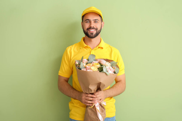 Delivery man with bouquet of flowers on color background - Photo, Image
