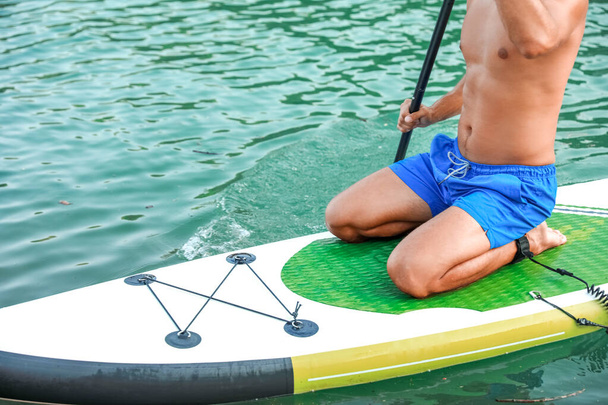 Giovane che utilizza il paddle board per sup surf nel fiume - Foto, immagini
