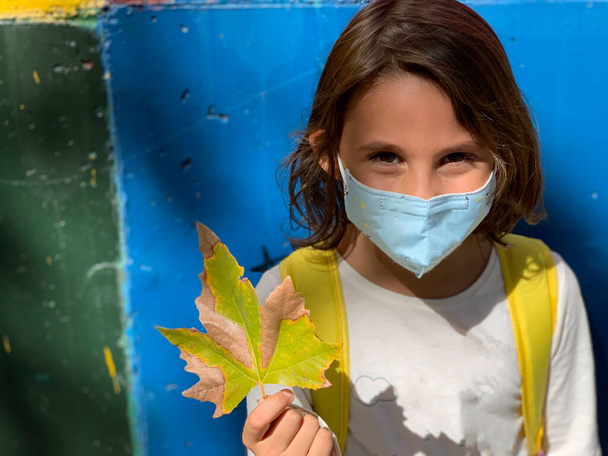 Дівчина з маскою, тримайте листок в осінній сезон
 - Фото, зображення