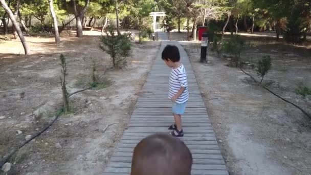 Söpö veljekset, taapero ja 4-vuotias kävely puinen patio puistossa.  - Materiaali, video