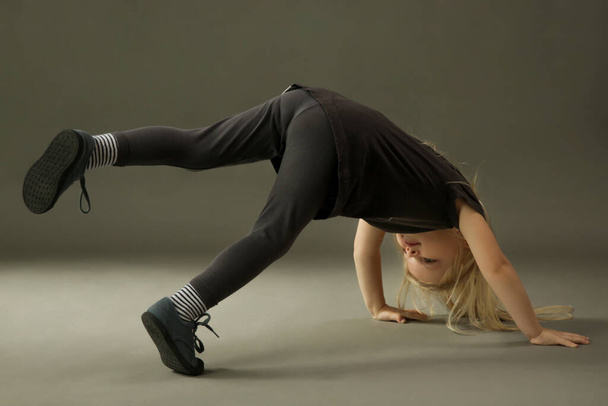Adorable niñito practicando break dance, estudio filmado sobre fondo gris - Foto, imagen