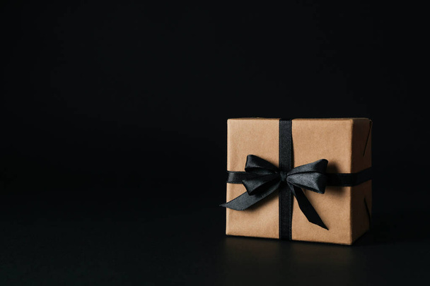 Gift box with black bow on black background - Foto, Imagen