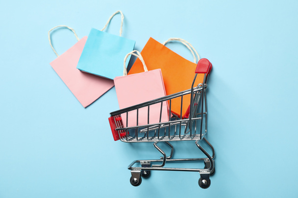 Shop cart with paper bags on blue background - Фото, изображение