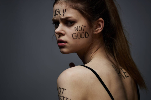Emotional woman with inscriptions on body upset with frustration gray background - Foto, immagini