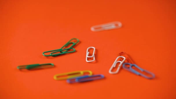 clipes de papel coloridos caem sobre a mesa. material escolar. clipes de papel de perto - Filmagem, Vídeo